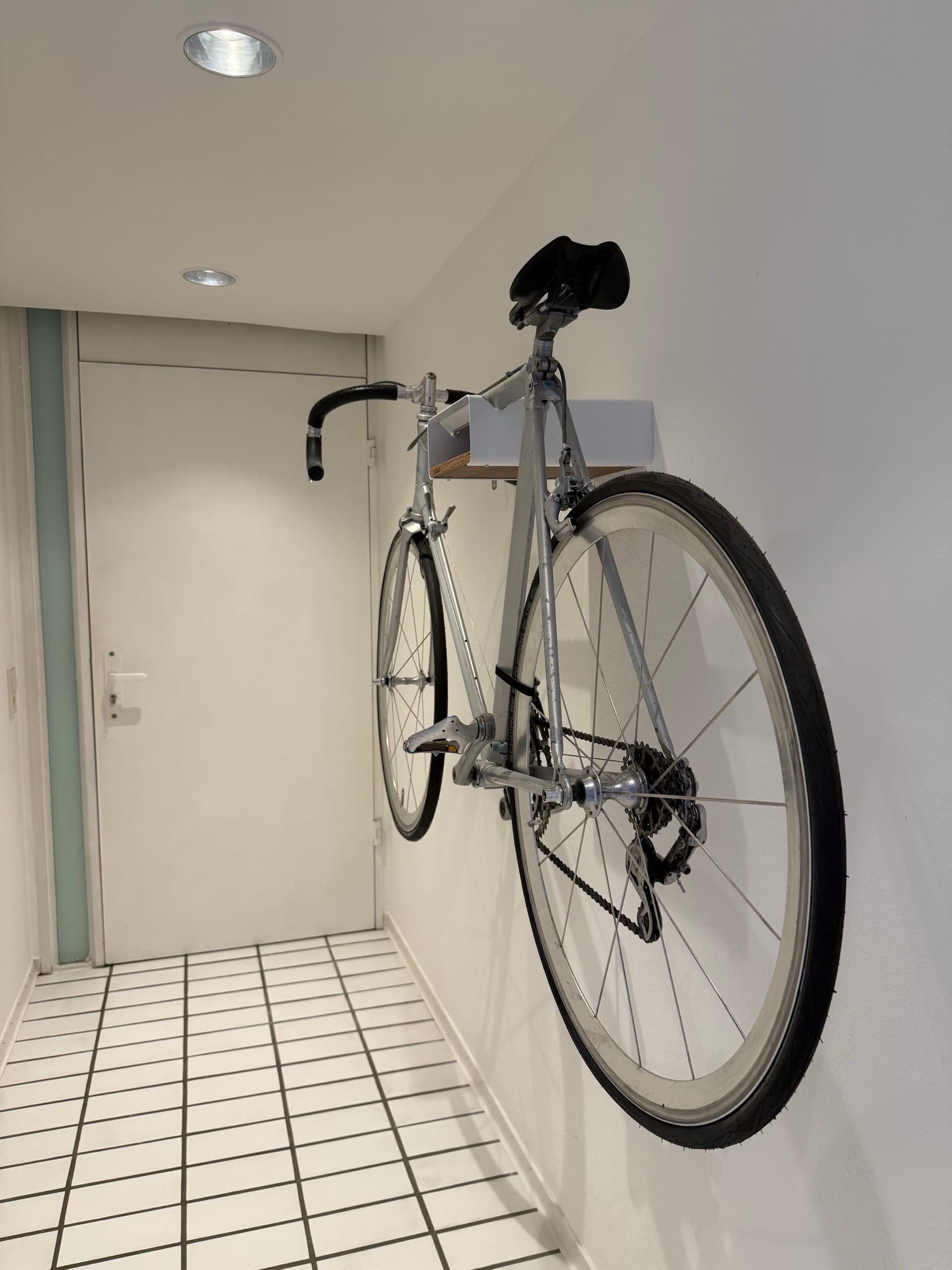 Silbernes Rennrad an einer Wandhalterung im Flur des Studios